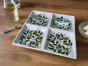 Decorative ceramic tray with green leaf patterns on a wooden surface