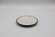 Round black and white patterned plate on a gray surface