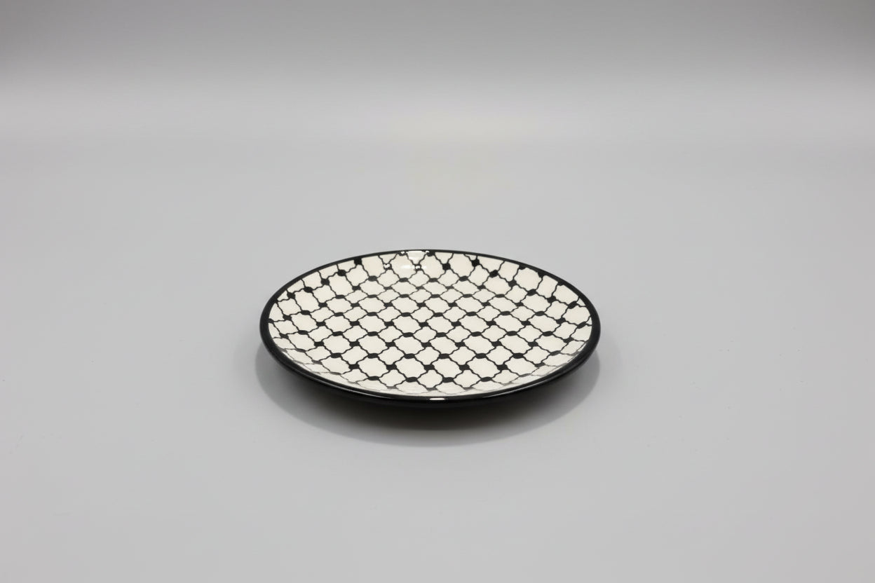 Round black and white patterned plate on a gray surface