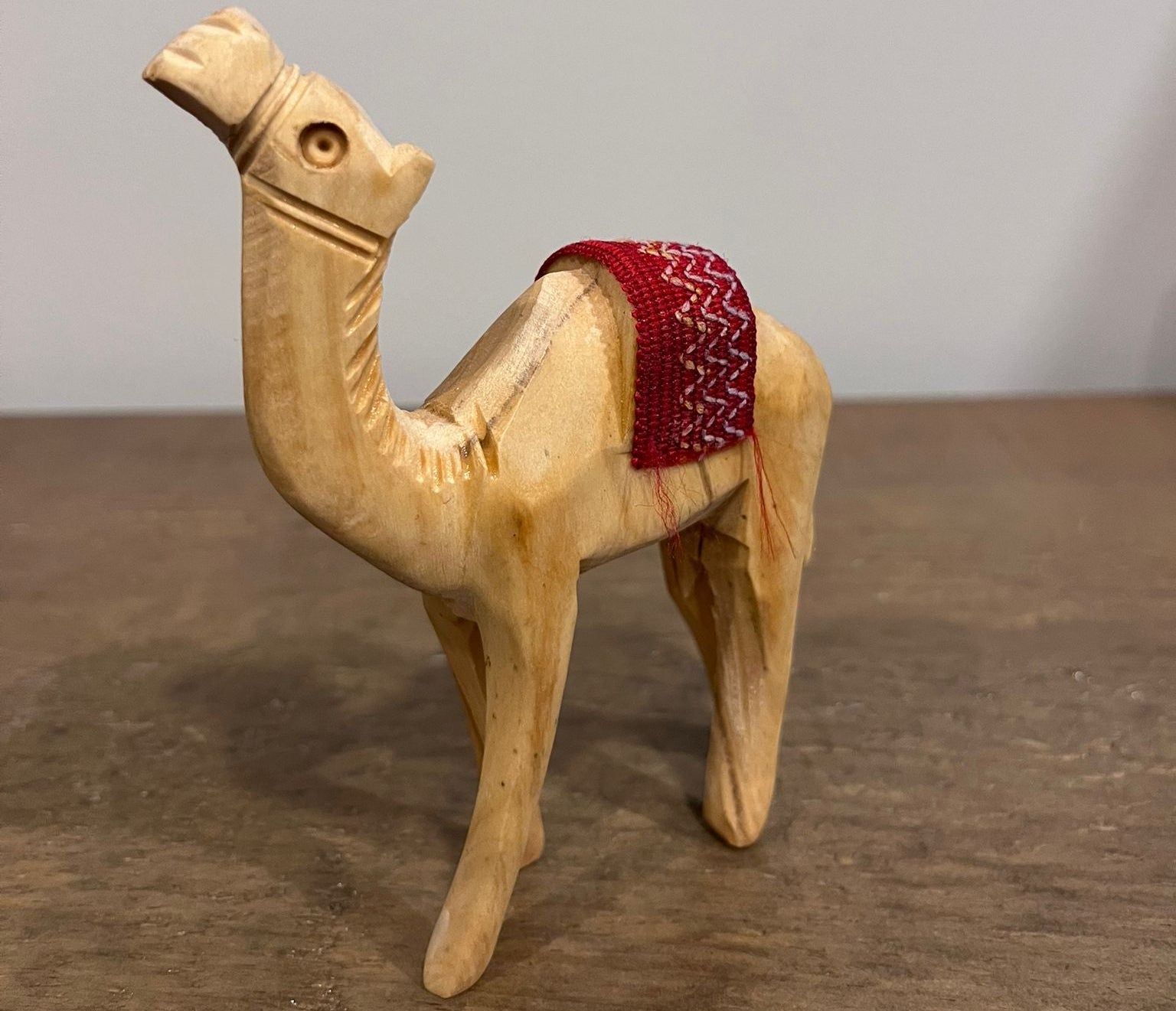 Hand-carved olive wood camel figurine with red woven saddle made in Palestine