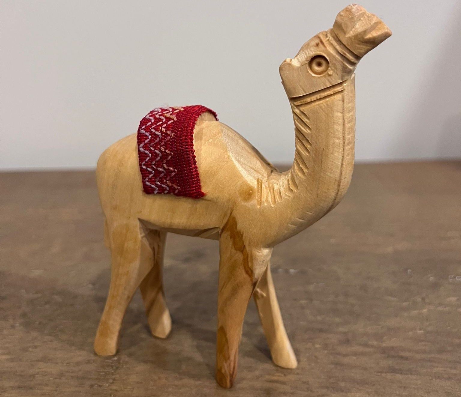 Hand-carved olive wood camel figurine with red woven saddle made in Palestine