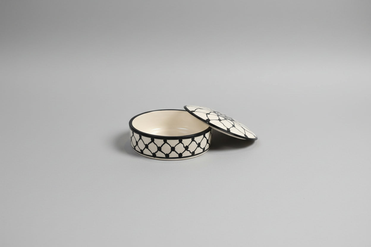 Round decorative box with a black and white pattern on a gray carpet