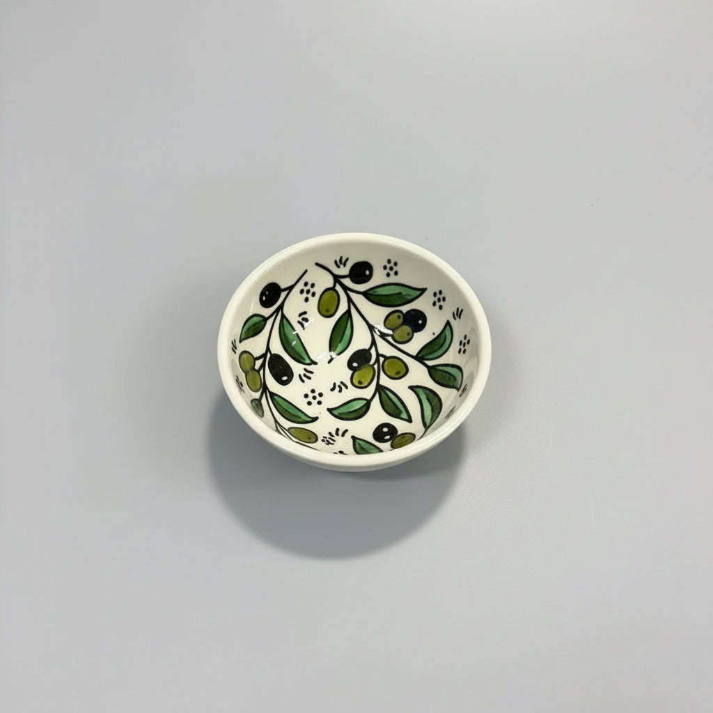 Small white ceramic bowl with green leaf pattern on a gray background