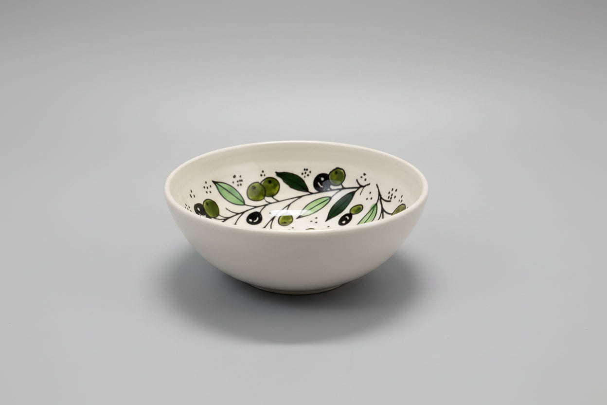 White ceramic bowl with green leaf design on a gray surface