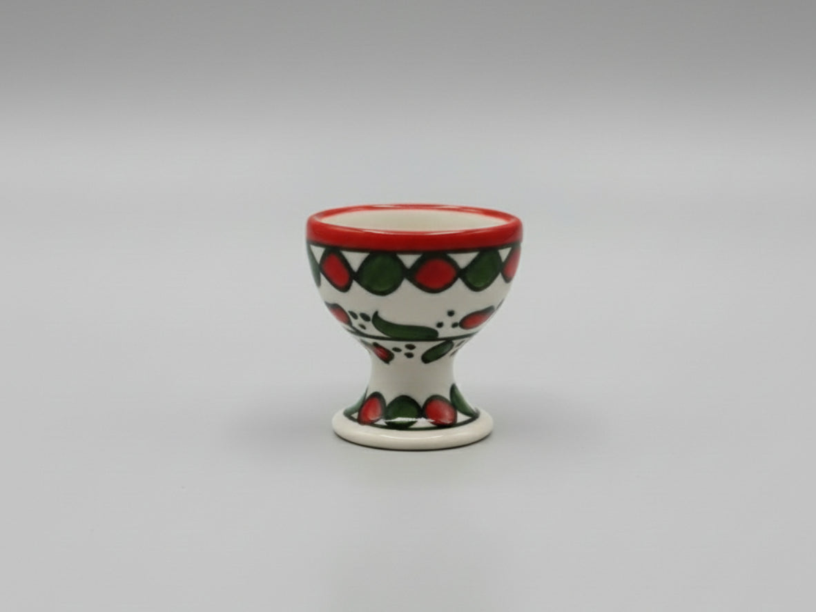 Ceramic egg cup with red and green pattern on a gray background